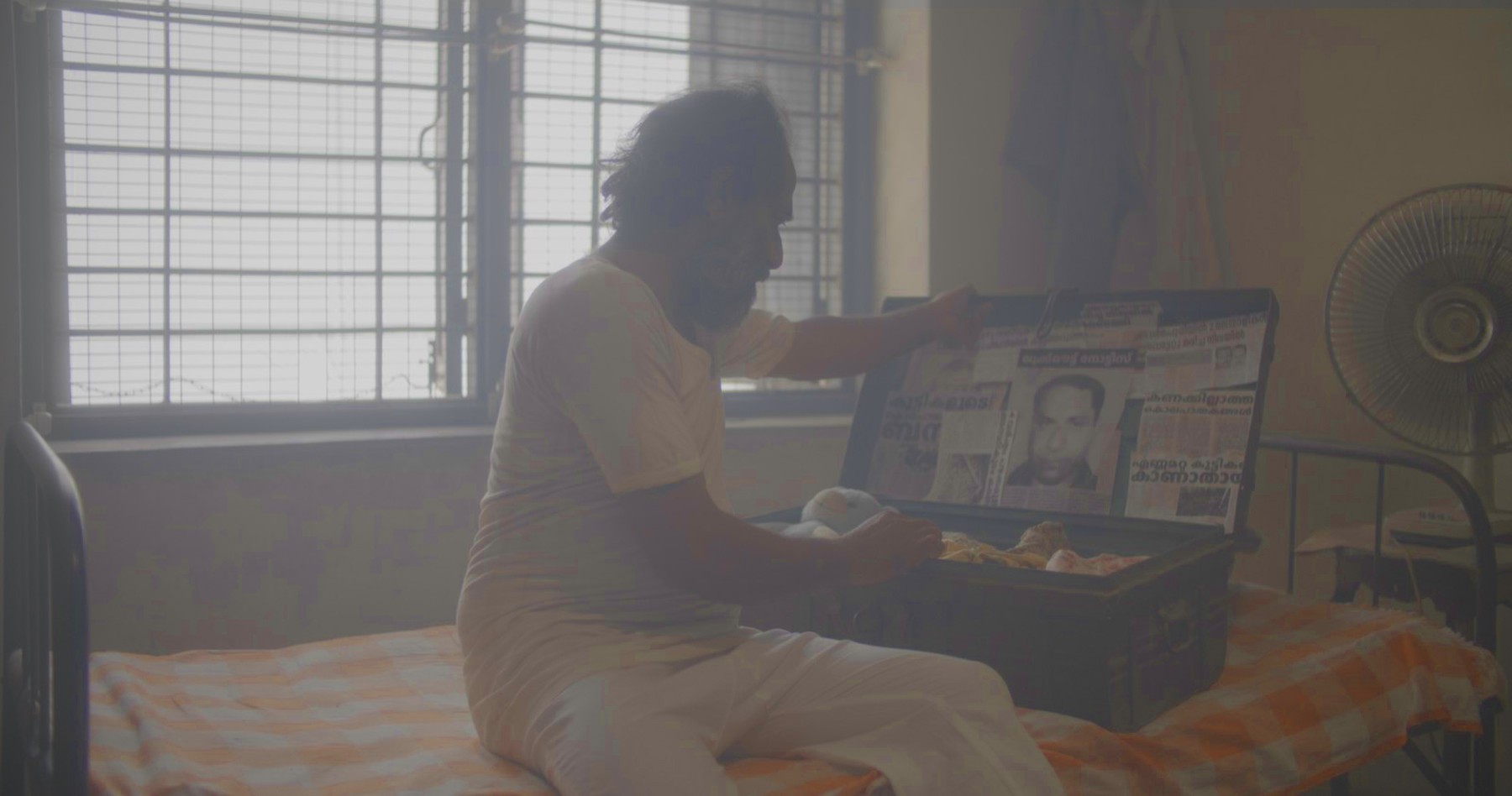 Man opening a trunk of newspaper clippings, still from Another Short Film About Killing
