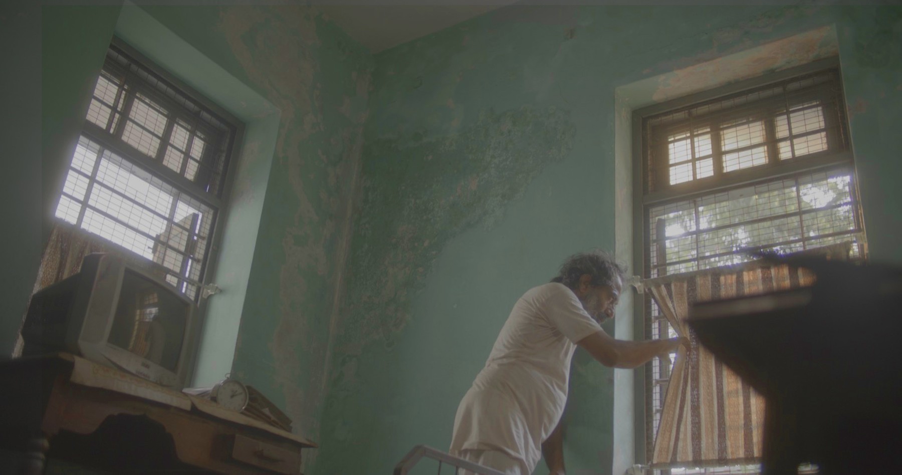 Man by a window in a weathered room, still from Another Short Film About Killing