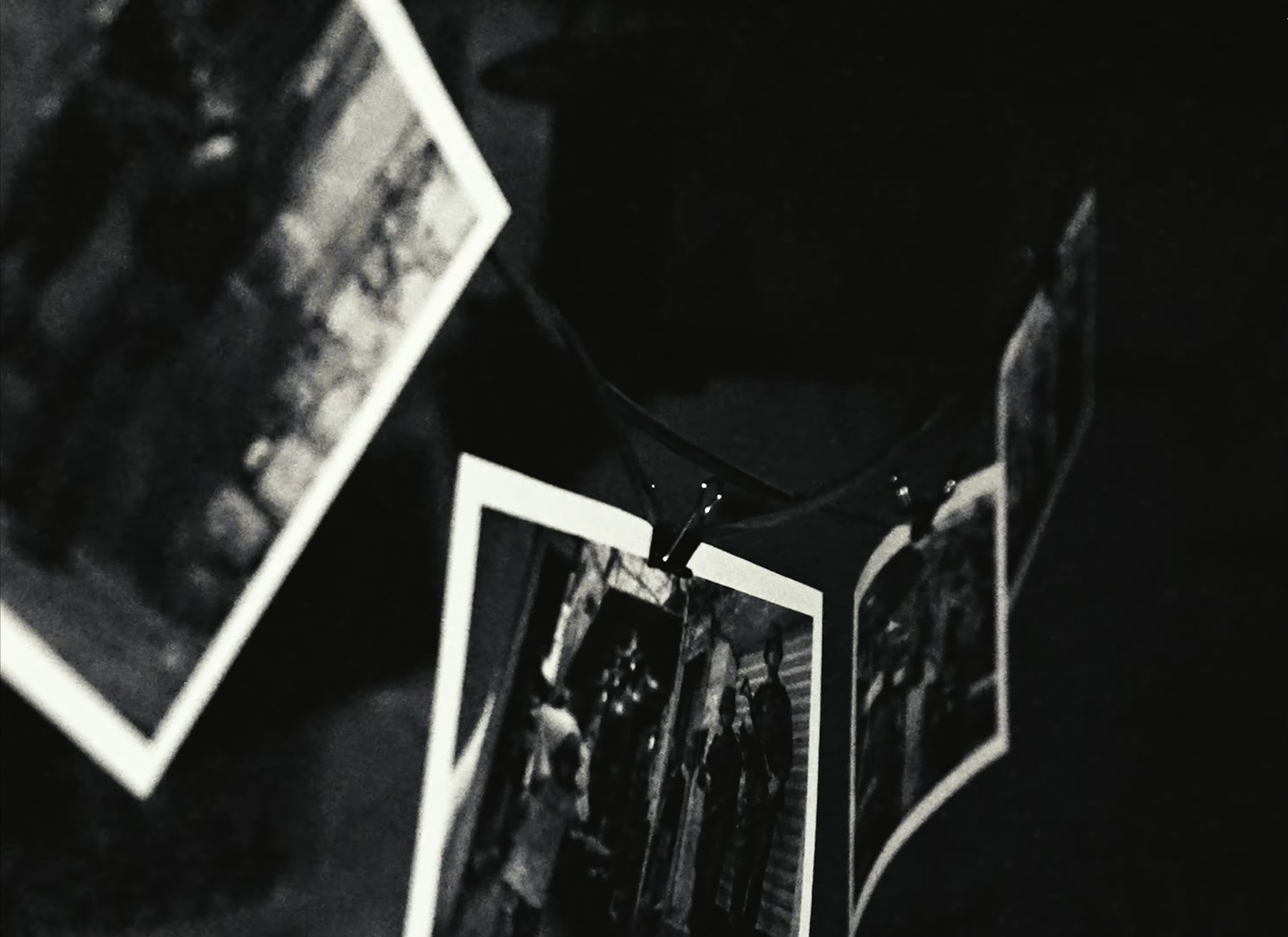 Photographs hanging on a line, still from Paychecks