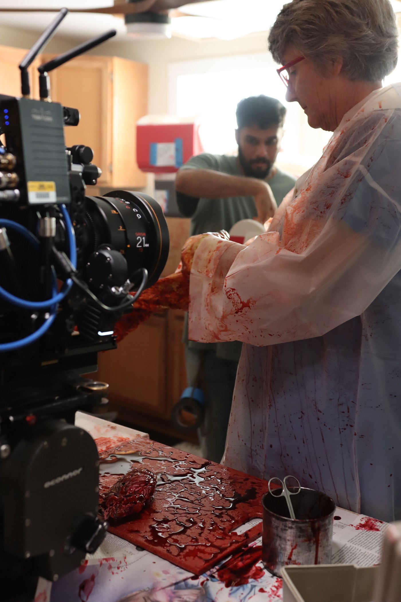 Crew member applying blood to a prosthetic prop on camera