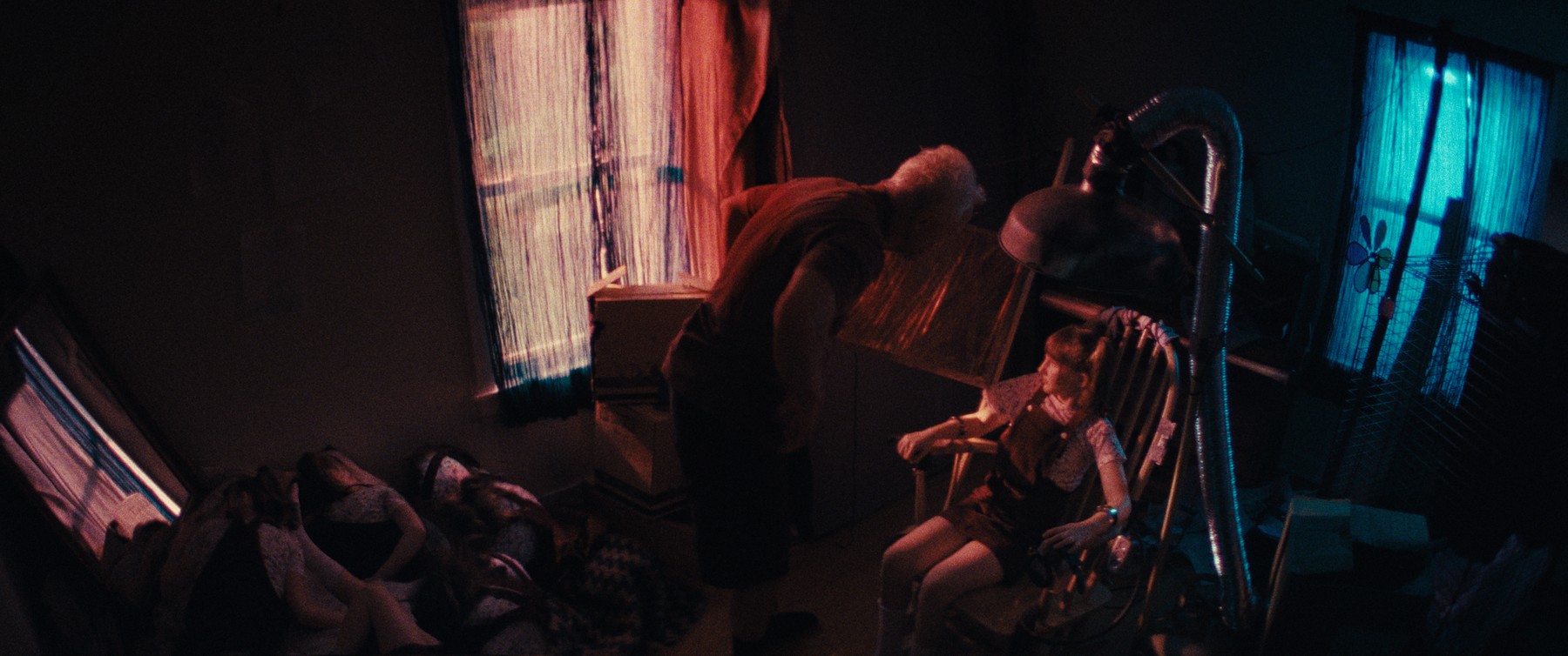 Dark room with girl figures seated and a looming silhouette