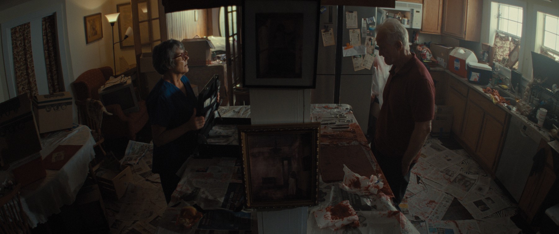Elderly woman and man examining a framed photograph in the kitchen